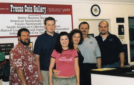 The Foster family behind the counter at Fresno Coin Gallery, in front of the membership board.